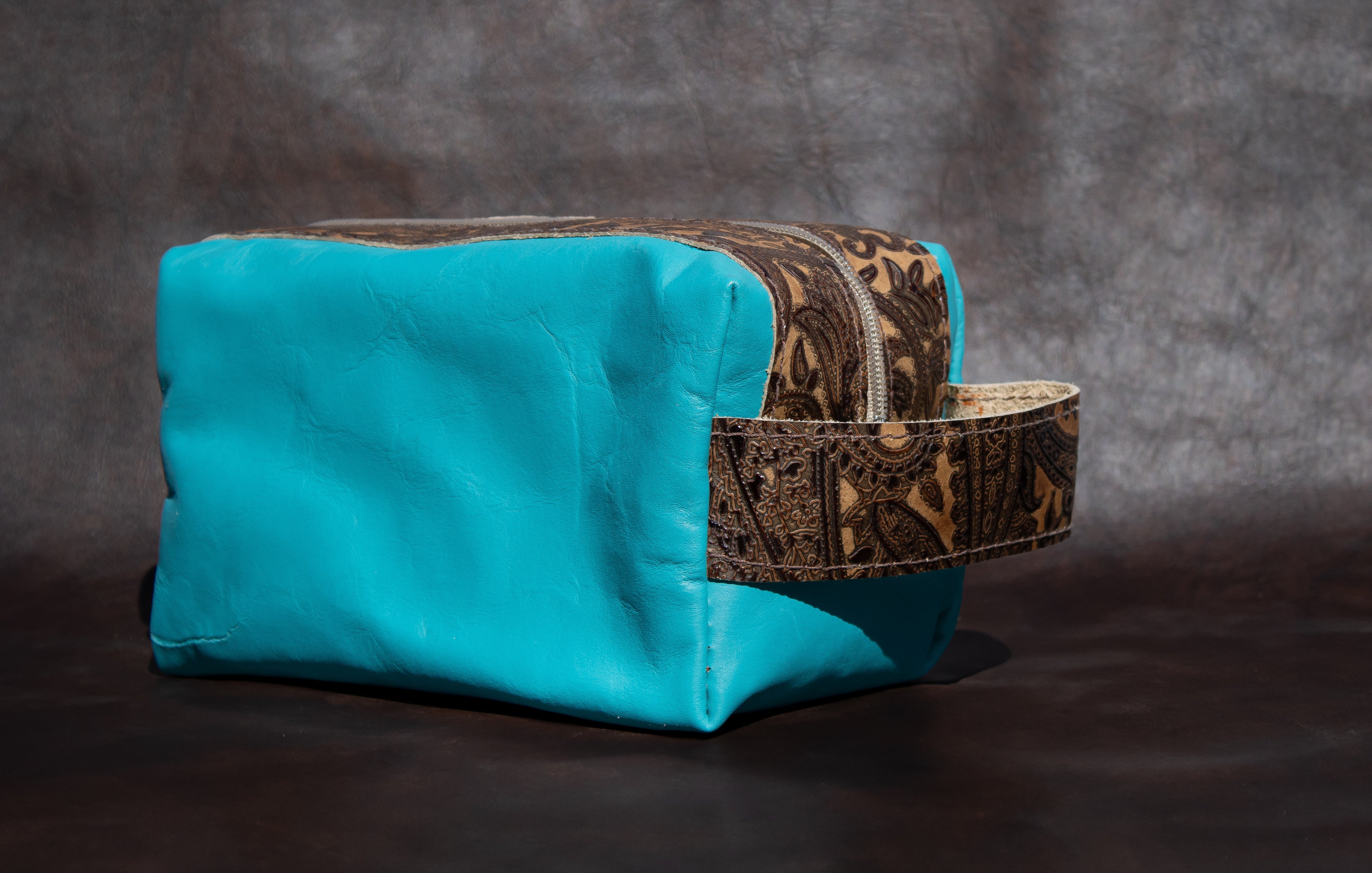 Turquoise bag with a decorative strap on a dark background