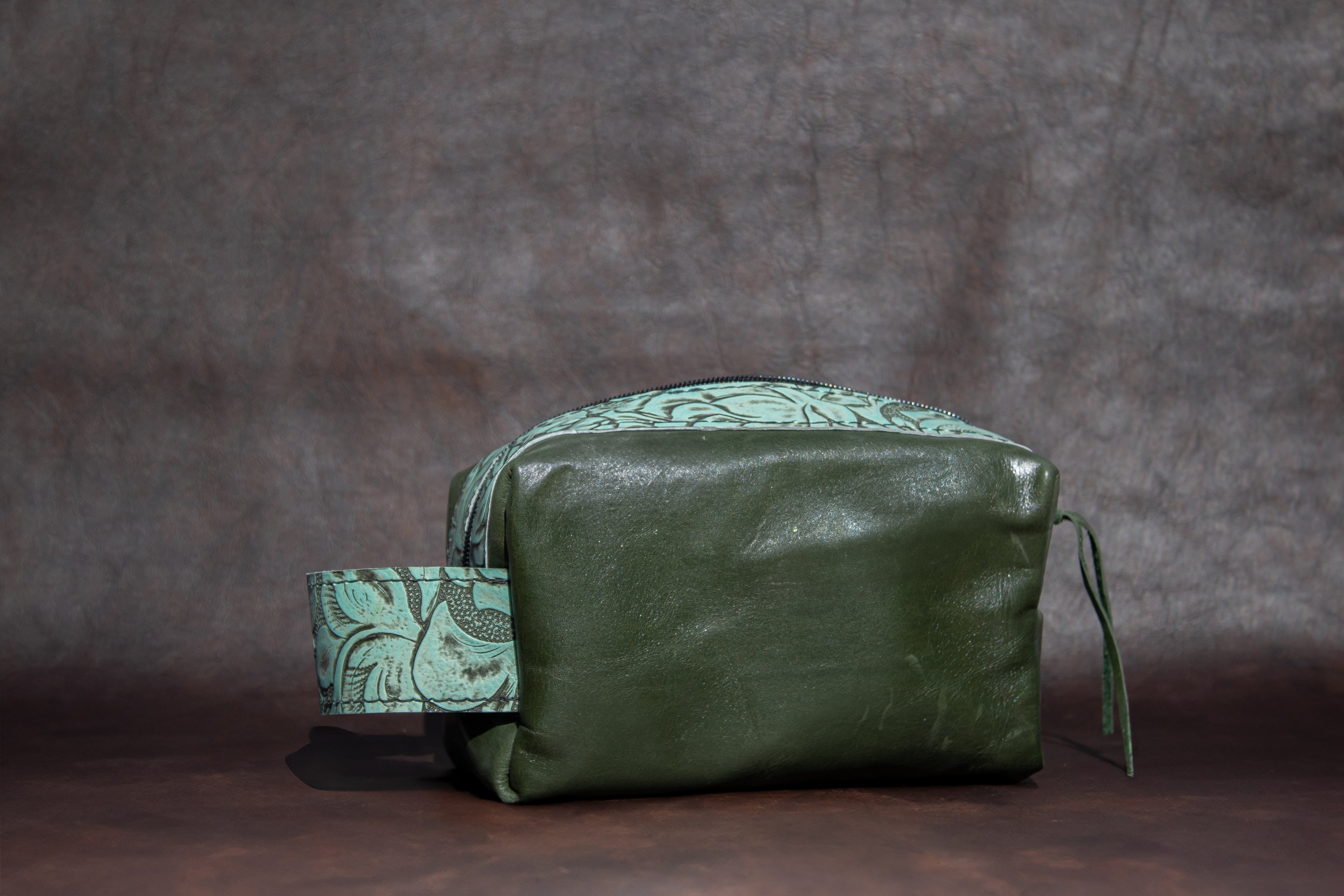 Green leather bag with patterned strap on a dark background
